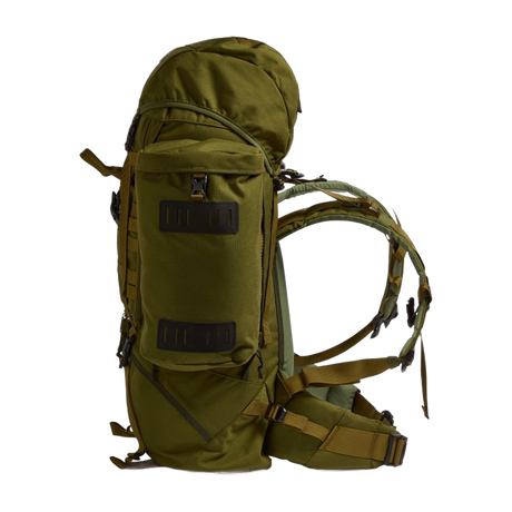 Side profile of the Crusader 90 + 20 FA military rucksack showing front access pocket, compression straps, and padded hip belt in olive green.