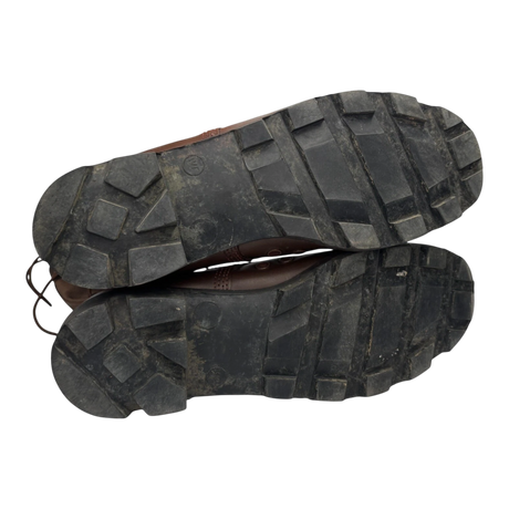 Underside of British Army Wellco combat boots displaying deep-lug rubber tread pattern with light signs of previous use, providing excellent grip for outdoor and tactical environments.